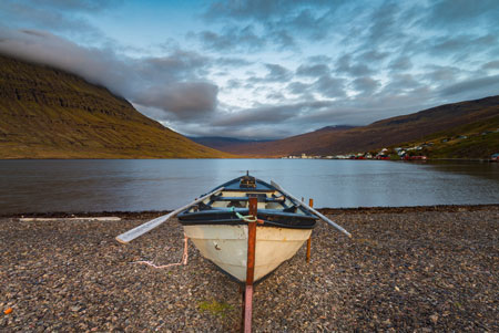 Rowboat aground in fjord at Eskifjorour Iceland with ocean and mountain background in Autumn