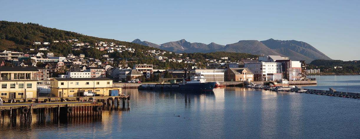 Buildings by the water with mountains in background, Harstad