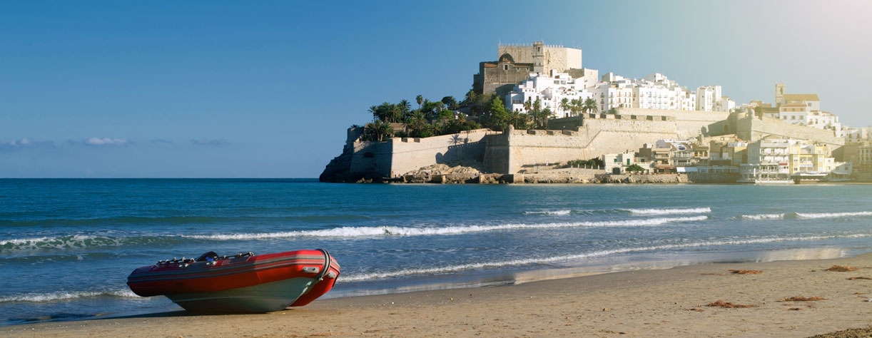 Rubber boat on the beach against Peniscola castle, Spain