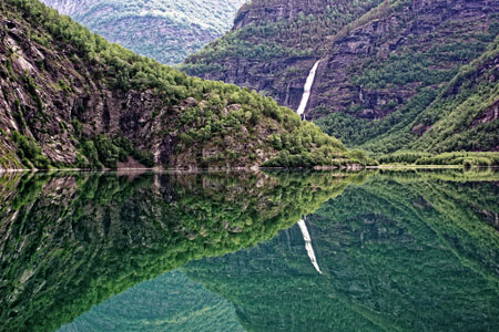 Rocks, mountains and waterfall mirrored in a river in Skjolden