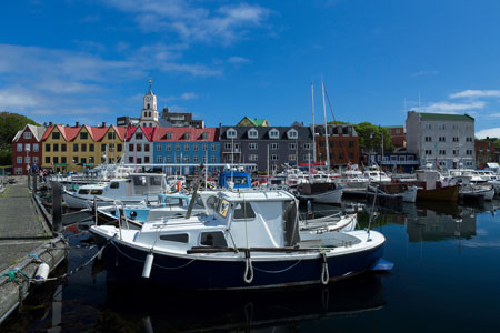 Boats in Marina Torshavn with colouful buildings and church