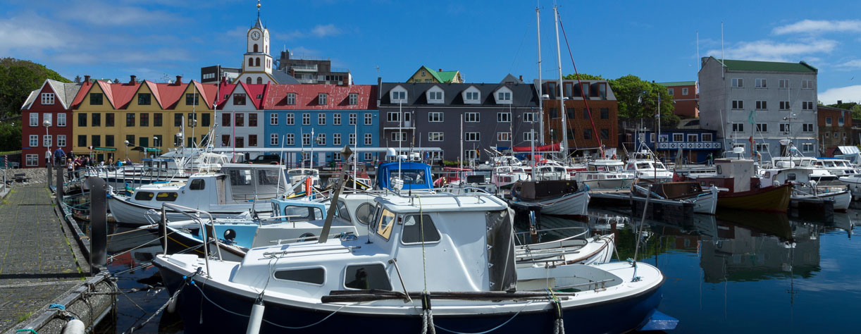 Boats in marina Torshavn Faroe Islands with colorful buildings and church in the background
