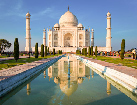 Taj Mahal on a bright and clear day at sunset reflects in the pond