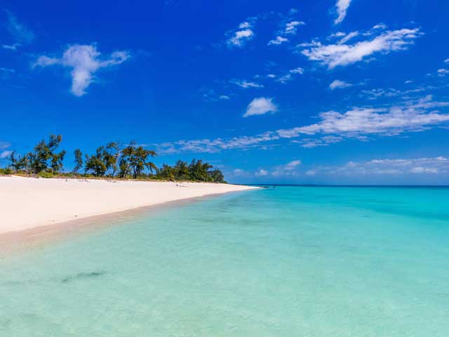 Idyllic tropical beach with white sand turquoise ocean water and blue sky