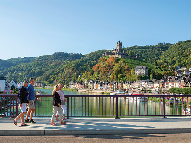 Friends walking across bridge in Cochem with Reichsburg Castle in the background, Germany Friends walking across bridge in Cochem with Reichsburg Castle in the background, Germany