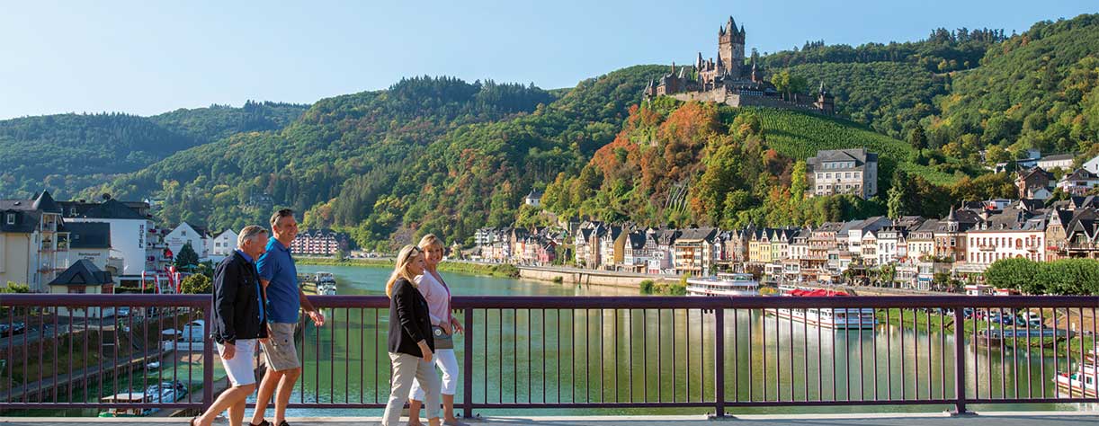 Friends walking across bridge in Cochem with Reichsburg Castle in the background, Germany Friends walking across bridge in Cochem with Reichsburg Castle in the background, Germany