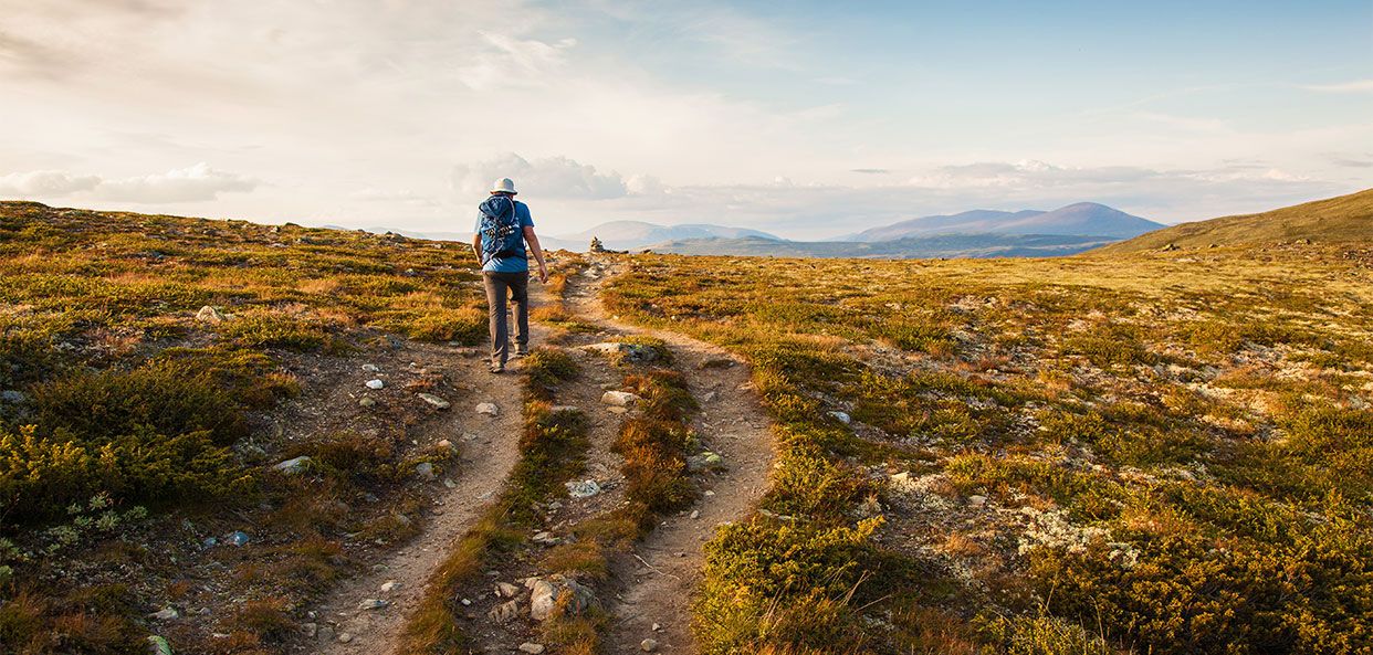 Hiker with backpack traveling in Norway mountains