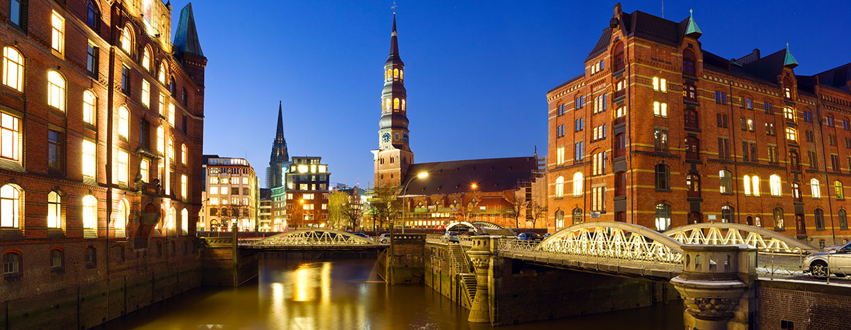 Warehouse district of Hamburg at night with view towards the city center including the St. Catherine's Church and St. Nikolai