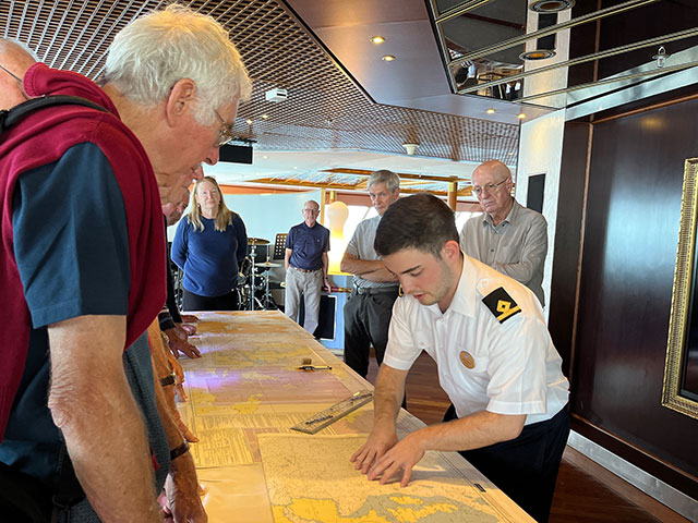 Officer and guests looking at navigational charts