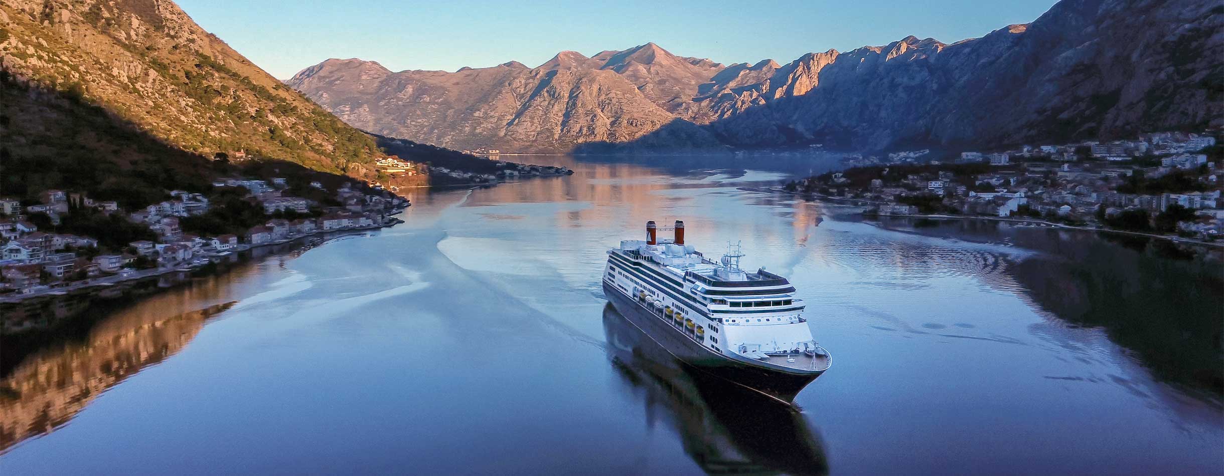 The Bolette ship docked in Kotor, Montenegro, against a backdrop of dramatic mountains and blue waters.