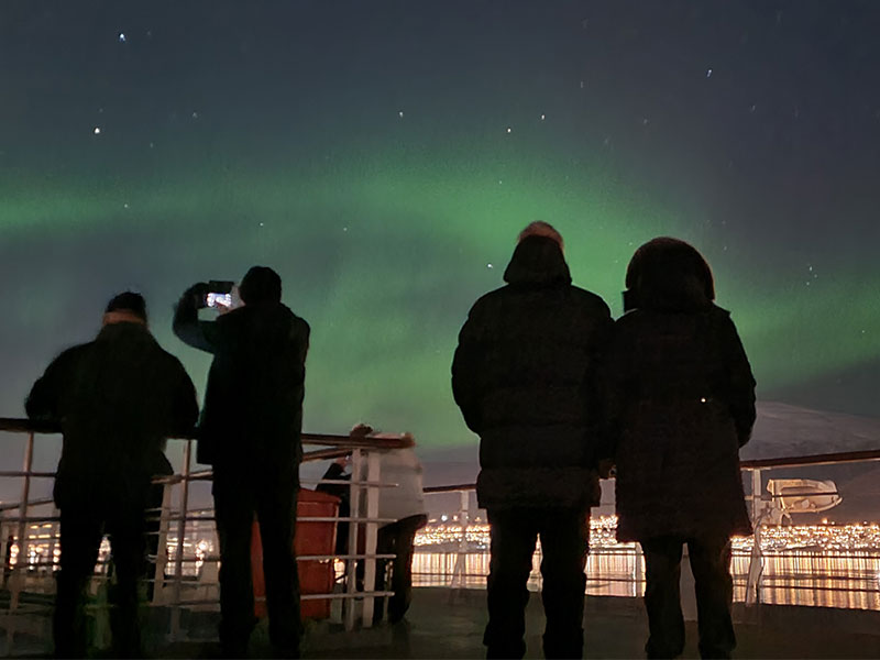 Guests looking out to Northern lights from deck