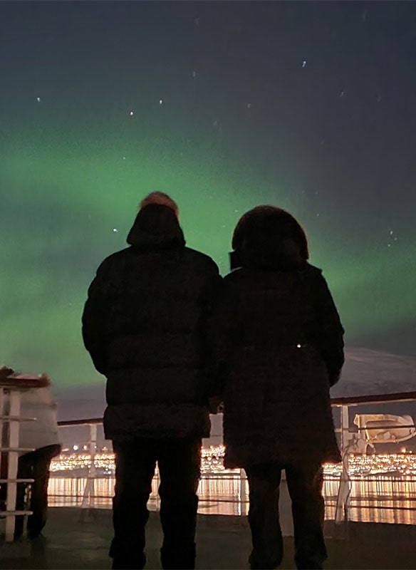Guests on deck looking out to the Northern lights, Norway