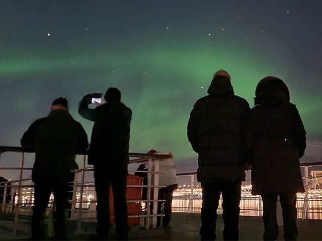 Guests on deck looking out to the Northern lights, Norway