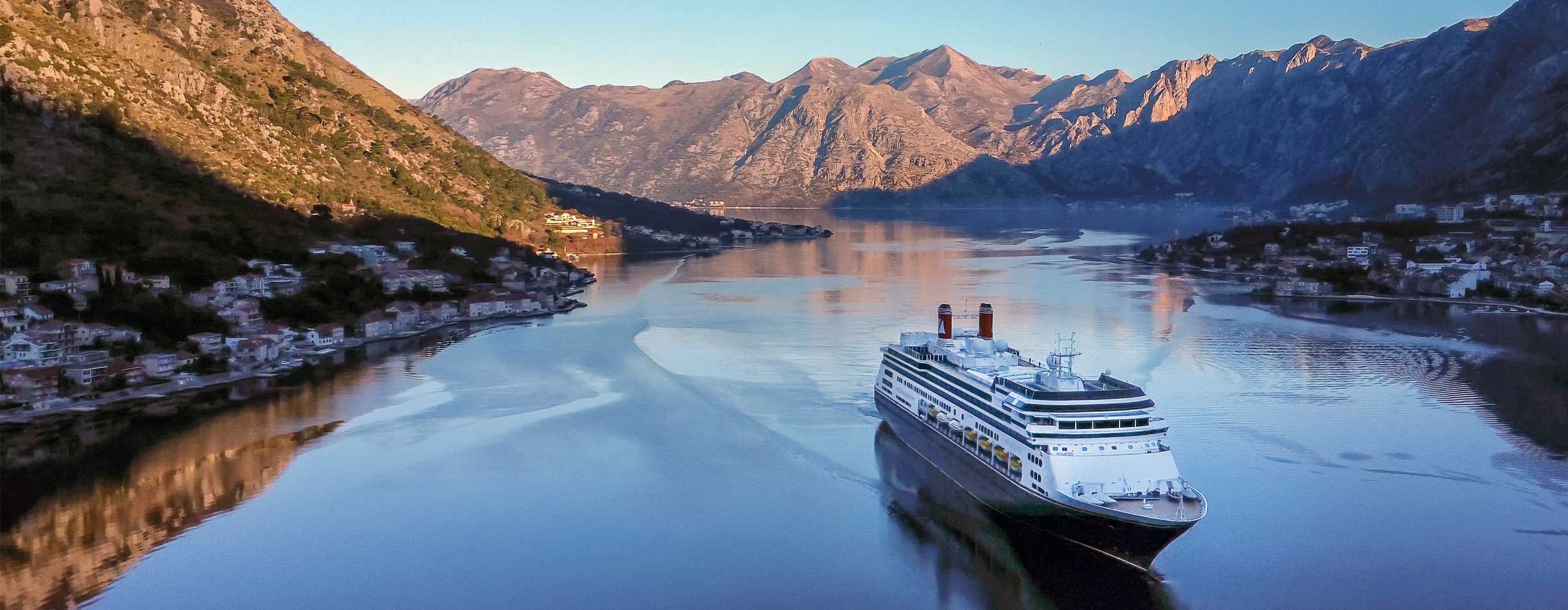 The Bolette ship docked in Kotor, Montenegro, against a backdrop of dramatic mountains and blue waters.