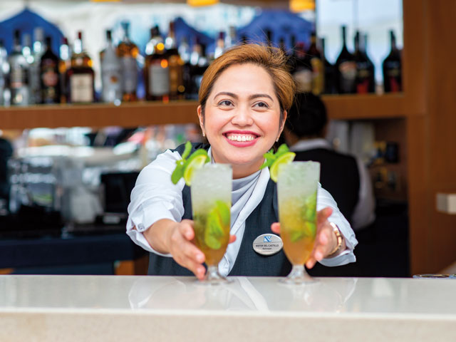Kiefer, a bartender, serving drinks at the Lido Bar on the Bolette, with a relaxed smile.