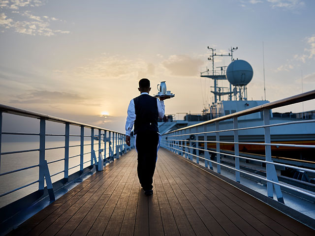 Waiter carrying drinks out on deck at sunset