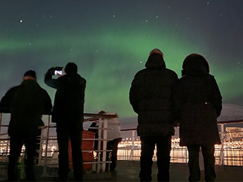 Guests on board watching the Northern lights from deck