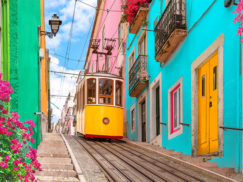 Yellow tram on a colourful street in Lisbon