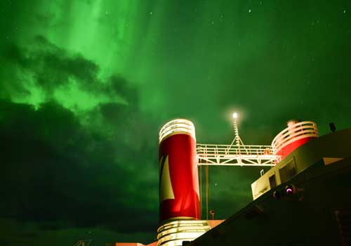 Borealis ship funnels with green Northern Lights in the night sky 