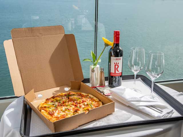 Room service delivery of Pizza and Red Wine on a table 