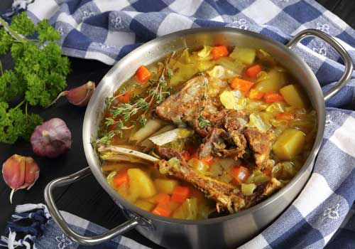 Icelandic Lamb winter hot Soup with vegetables and spices in a stainless steel casserole pan