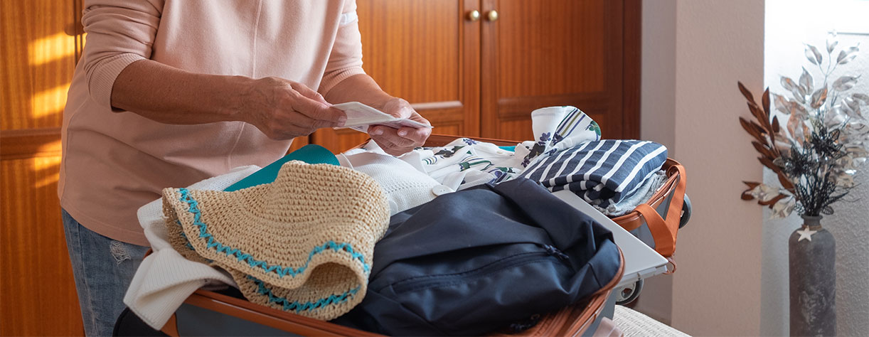 Mature lady packing clothes and checking list for travel