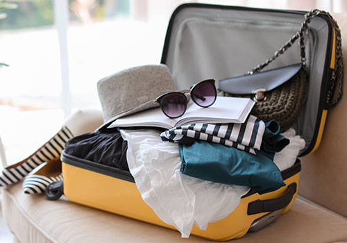 Open yellow suitcase with different clothes packed for travel