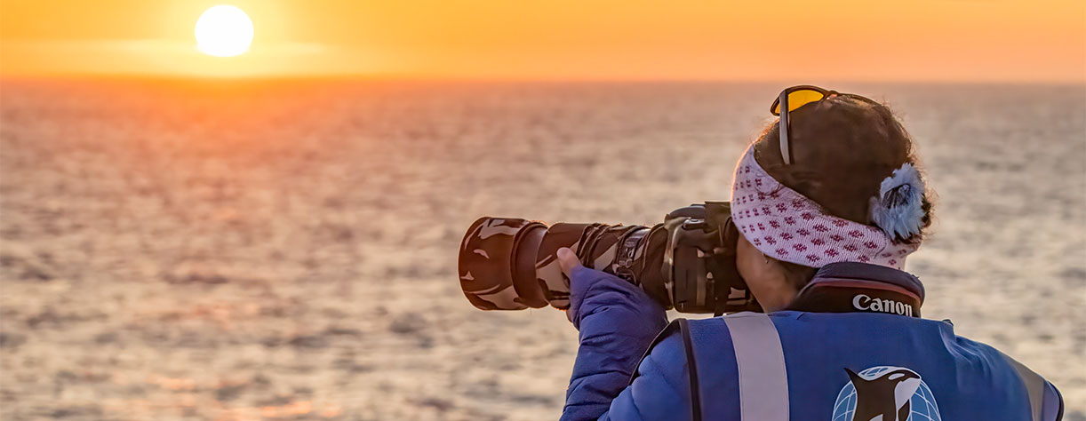 ORCA looking out to sea from deck, with camera at sunset