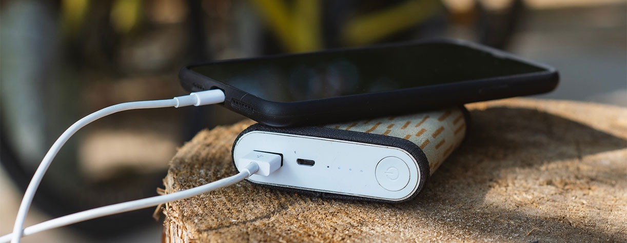Phone plugged into portable charger on a fence