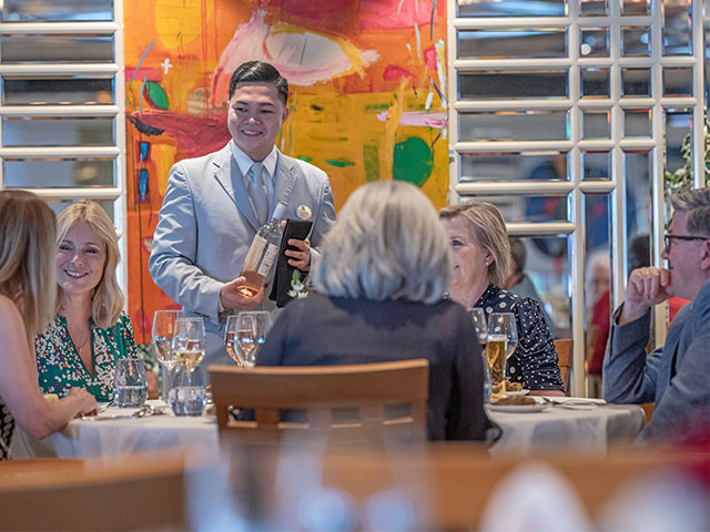Guests dining in the Ballindalloch restaurant, with waiter serving wine, Balmoral