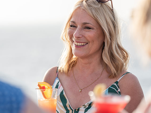 Guest on deck smiling with drink