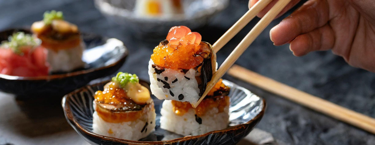 An image of a person eating sushi with chopsticks
