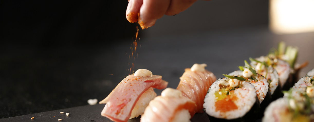 A chef seasoning Sushi with some spice