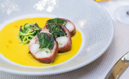 monkfish with spinach and pancetta, courgetti strands and creamy saffron bisque