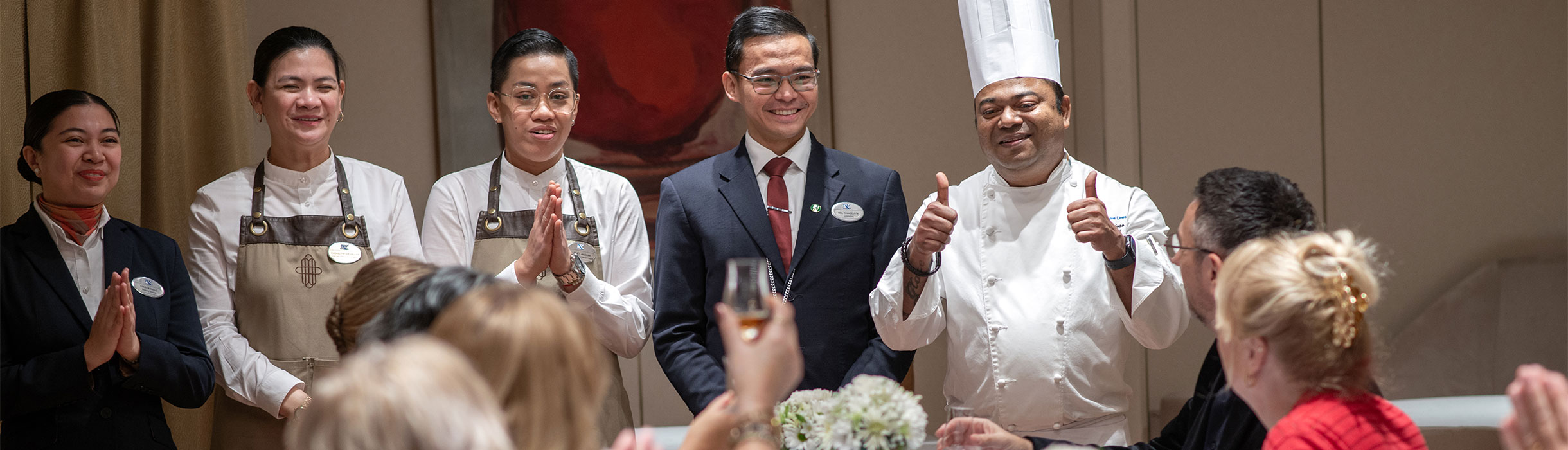 Waitresses, Sommellier and Executive chef at the Chefs table with guests