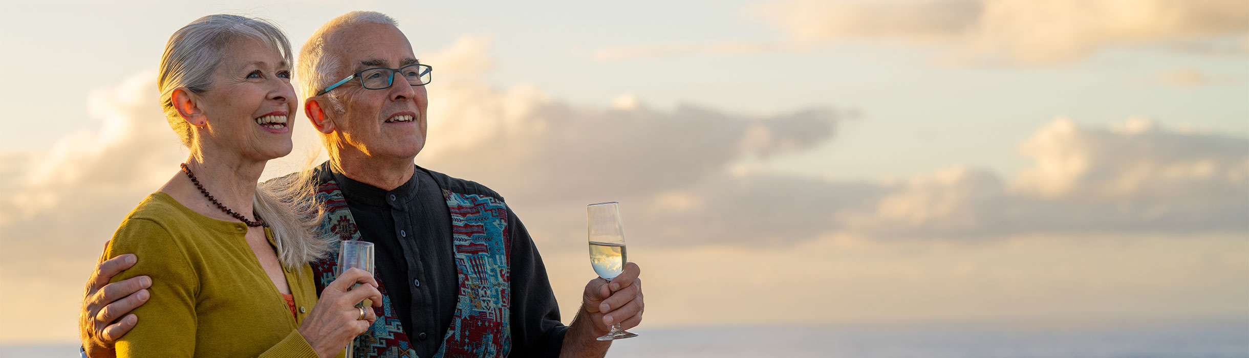 Guests on deck with drinks, looking out to sea