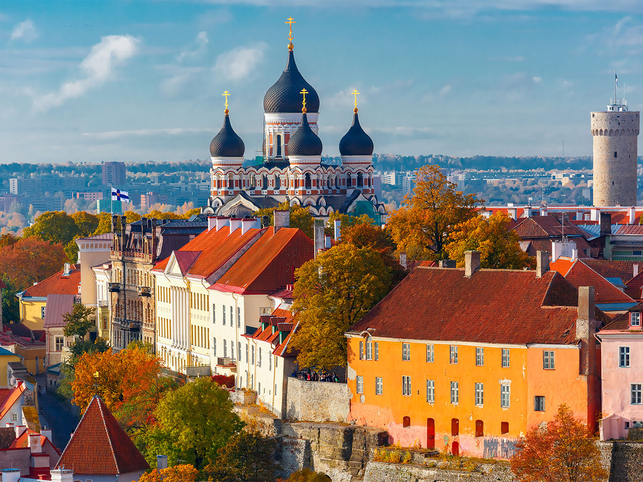 Aerial view of Tallinn's Old Town in Estonia, with Alexander Nevsky Cathedral's dark domes rising above red-roofed buildings and autumn trees.